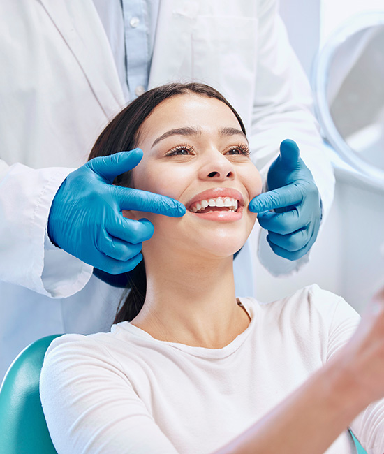 The image shows a dental professional performing a teeth cleaning procedure on a patient, with the patient smiling and appearing relaxed in an office setting.